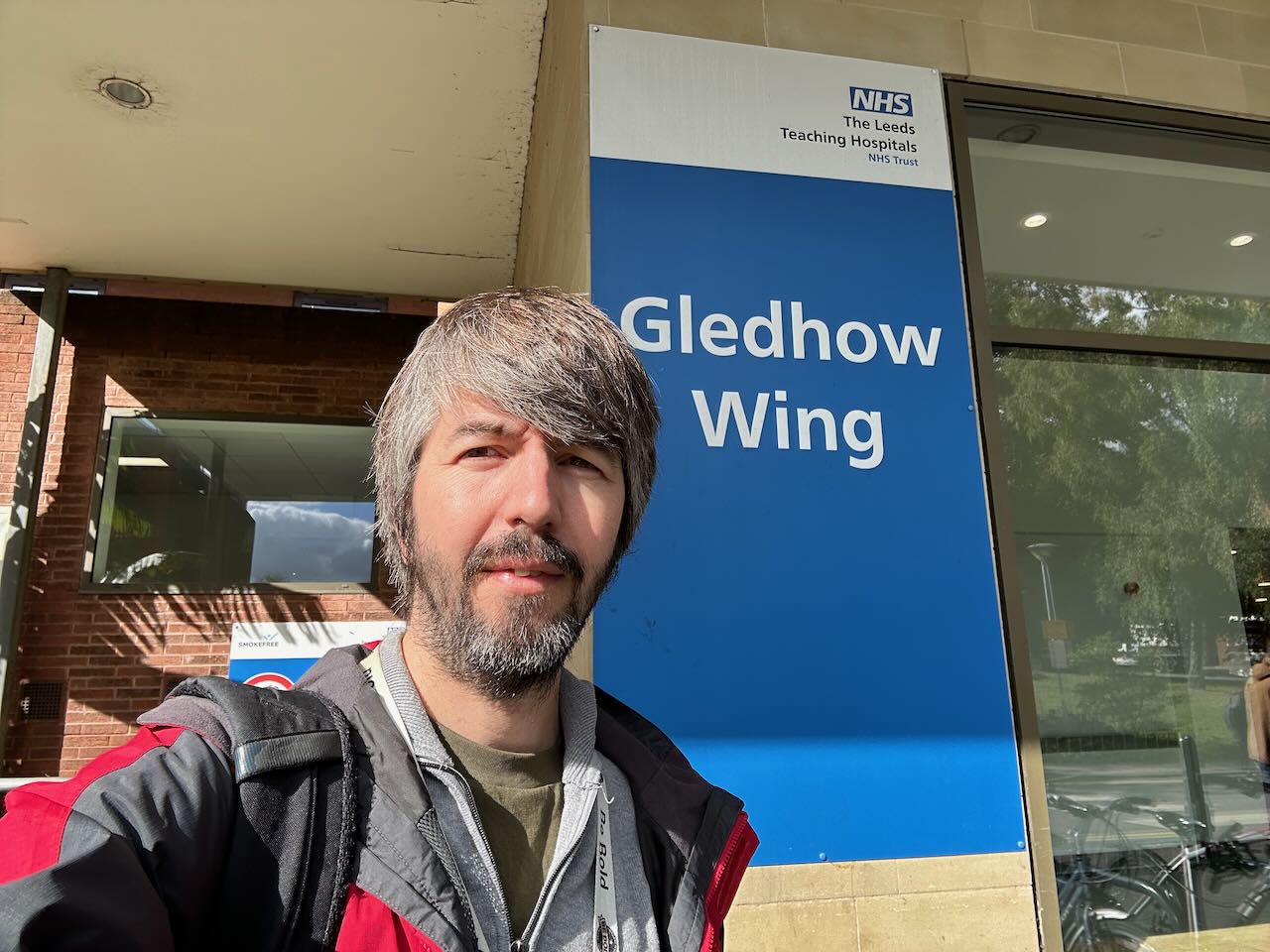 Photo of me outside a hospital entrance with a sign saying Gledhow Wing