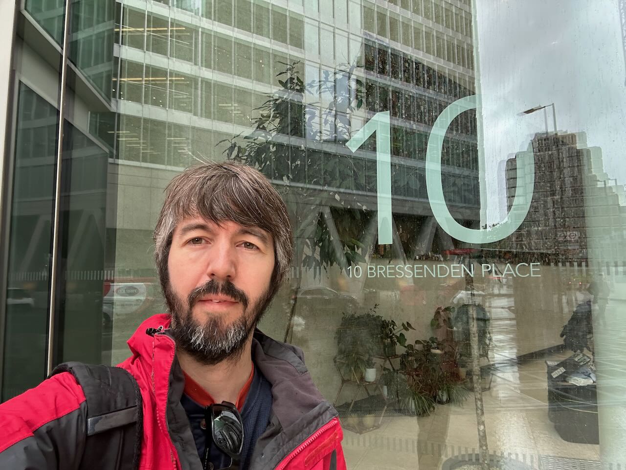 Photo of me outside a shiny glass office building labelled 10 Bressenden Place